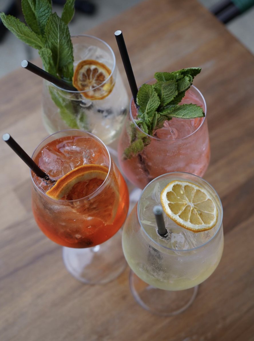Four spritzes with mint and dried citrus on a wooden table