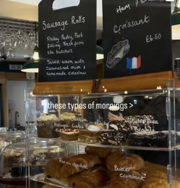 The pastry counter at The Little Deli, with croissants and cakes under the chalkboard menus